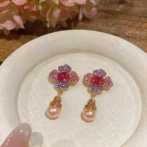 Detail view of elegant flower earrings with pink crystals and pearl pendants.
