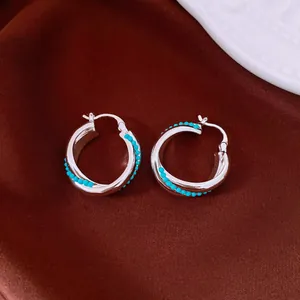 Macro view showing the intricate turquoise bead inlay on silver vintage hoop earrings.