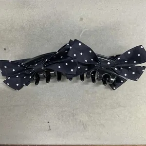 Dettaglio della pinza per capelli nera con fiocchi a pois bianchi eleganti.