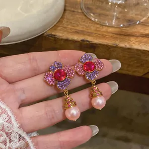 Detail view of elegant floral earrings with pink pearl drops and colorful pavé stones