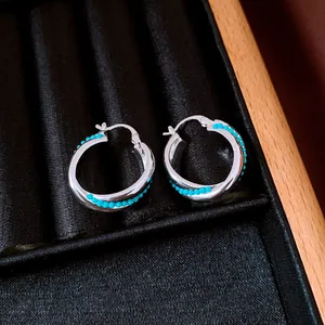 Macro view of vintage silver hoop earrings accented with turquoise beads in a display box.