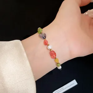 Close-up of a colorful stone and pearl beaded bracelet on a woman's wrist