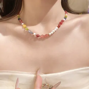 Close-up of a colorful gemstone bead and pearl necklace on a model's collarbone.