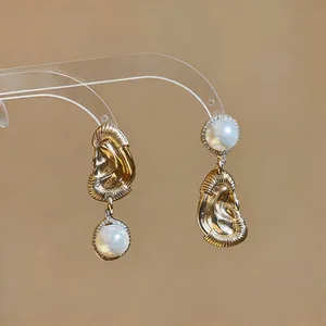 Dettaglio degli orecchini dorati stile palazzo vintage con perle e strass brillanti