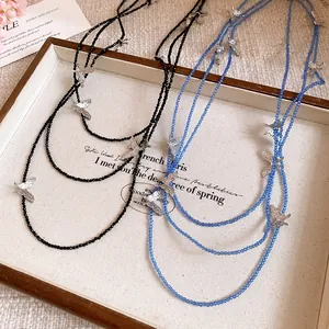 Close-up of blue and black beaded layered necklaces with silver butterfly charms