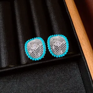 Macro view of vintage silver oval hollow mesh earrings with turquoise beads and zircon