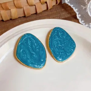 Dettaglio dei orecchini geometrici irregolari in smalto blu con bordo dorato
