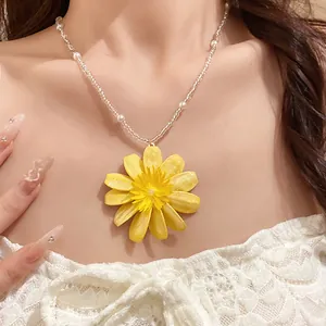 Gros plan d'un collier de perles marguerite jaune doux pour un look de vacances à la plage.