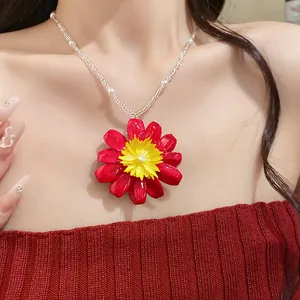 Vue détaillée d'un collier de perles marguerite rouge vif porté par un mannequin de mode.