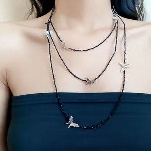Detailed view of layered necklace featuring black glass beads and silver butterfly charms