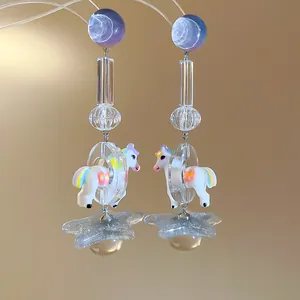 Close-up of whimsical resin unicorn and glitter star earrings with colorful beads