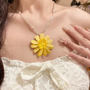 Vue détaillée d'un collier de perles marguerite jaune sur dentelle blanche.