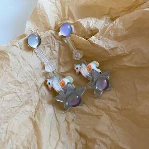 Detailed view of resin unicorn and star drop earrings on kraft paper background