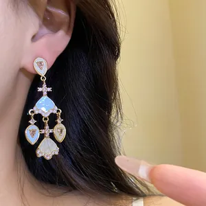 Gros plan de boucles d'oreilles vintage dorées avec zircons roses et acétate bleu.