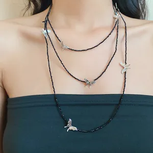 Close-up view of a layered black glass bead necklace with silver butterfly charms