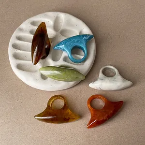 Close-up of multi-colored resin rings with unique geometric shapes on a display stone.