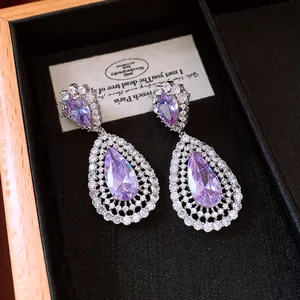 Detail shot of purple teardrop earrings with zircon halo in a gift box