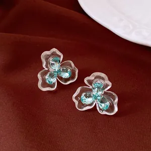 Detailed view of clear flower stud earrings with three central light blue crystals.