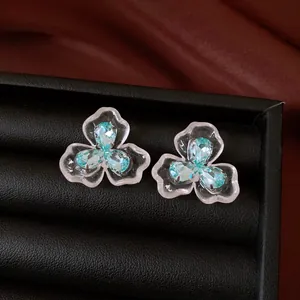 Detailed close-up of flower stud earrings with light blue zircons in a black jewelry box