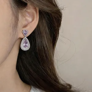 Detailed close-up of elegant hollow pear-shaped silver drop earrings with pink zircons