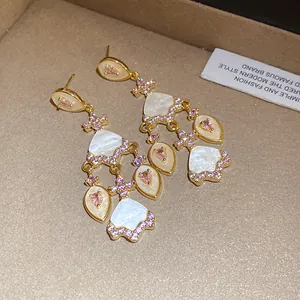 Vue détaillée de boucles d'oreilles vintage avec des zircons roses et de l'acétate blanc