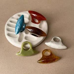 Collection of six colorful resin oval rings with marbled texture on minimalist display tray