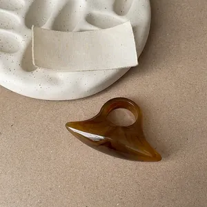 Detail shot of a chunky translucent amber resin ring in a minimalist geometric design.