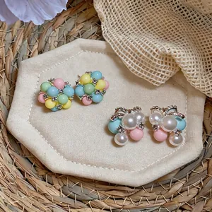 Macaron colorful acrylic bead stud earrings and pearl bow earrings on a beige tray