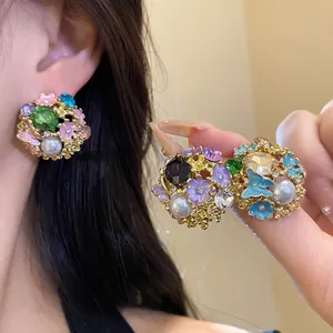 Detail view of vintage flower stud earrings with colorful enamel, crystals and pearls.
