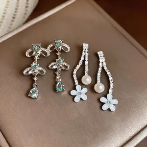 Elegant zircon and pearl drop earrings with white resin flower detail.