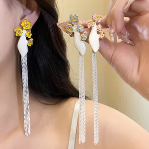Détails des boucles d'oreilles vintage en émail avec fleurs et longues chaînes argentées.