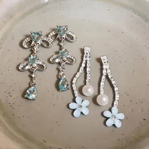 Elegant drop earrings with light blue zircon, white pearls, and resin flowers.