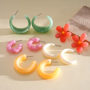Collection of colorful dopamine resin flower and twisted hoop earrings set on a stone prop