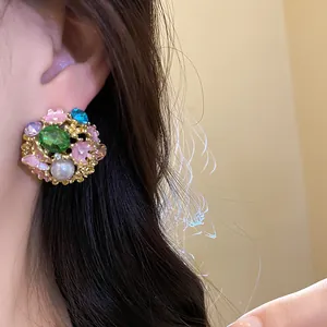Close-up of vintage flower stud earring featuring a green gemstone and pearl on ear