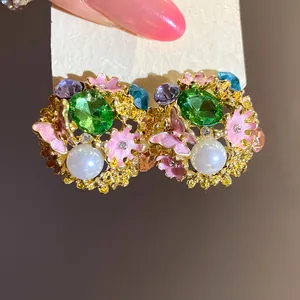 Detailed view of vintage palace style floral earrings with green stones and pearls