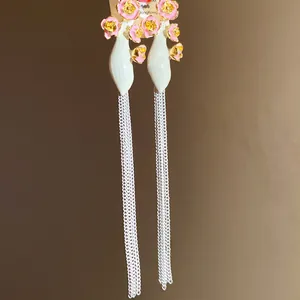 Gros plan de boucles d'oreilles vintage fleurs en émail rose et glands argentés.