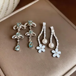 Detail view of zircon blue crystal and pearl resin flower drop earrings in silver