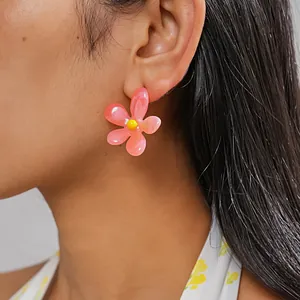 Detailed view of a vibrant pink resin flower earring worn by a model for dopamine style