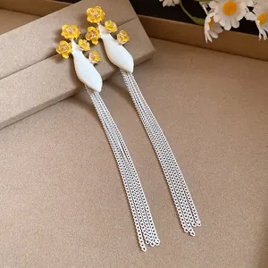 Gros plan de boucles d'oreilles vintage à pampilles avec fleurs jaunes et base blanche