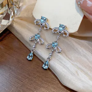 Detailed view of silver-tone drop earrings with light blue heart and pear-shaped stones.