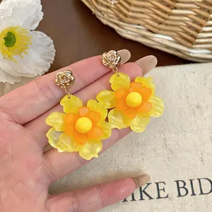 Detailed macro view of vibrant yellow resin flower earrings with elegant golden rose studs.