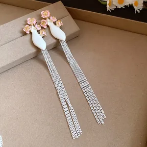 Détail des boucles d'oreilles vintage de style cour avec des fleurs et des glands.