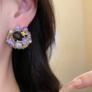 Macro view of vintage palace-style stud earring featuring purple enamel flowers and pearl
