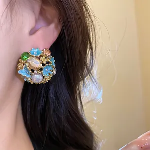 Close-up shot of a vintage style floral earring with colorful crystals and pearl on ear