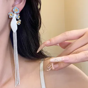 Gros plan de boucles d'oreilles à pompons de style vintage avec des fleurs bleues