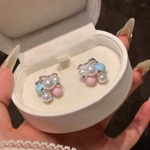 Close-up of macaron colored pearl stud earrings with rhinestones in a white gift box