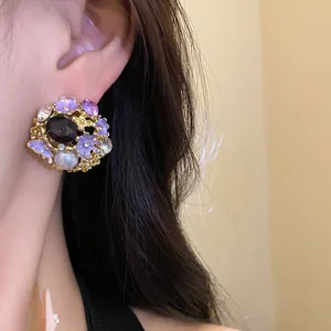 Detailed close-up of a vintage palace style flower earring with pearl and purple enamel.