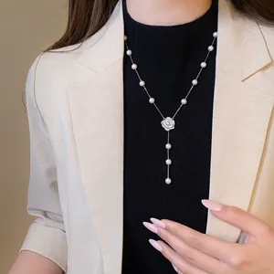 Beautiful camellia flower pendant pearl necklace worn by model in elegant attire