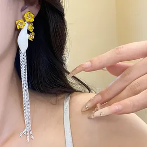 Gros plan de boucles d'oreilles vintage fleurs émaillées jaunes avec longs pompons