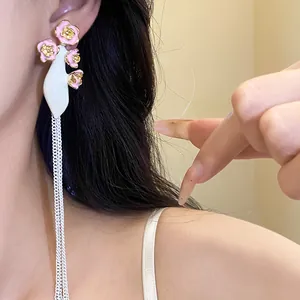 Détail de boucles d'oreilles vintage avec fleurs en émail rose et glands d'argent